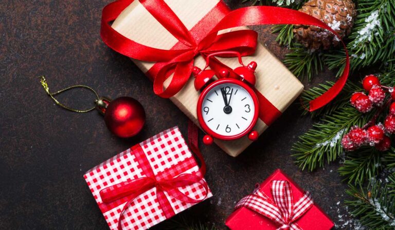 Christmas gifts with red alarm clock showing two minutes to midnight