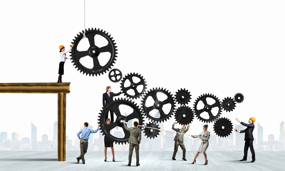 tiny businesspeople fitting together large gears