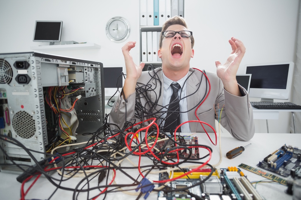 Stressed computer engineer working on broken cables in office