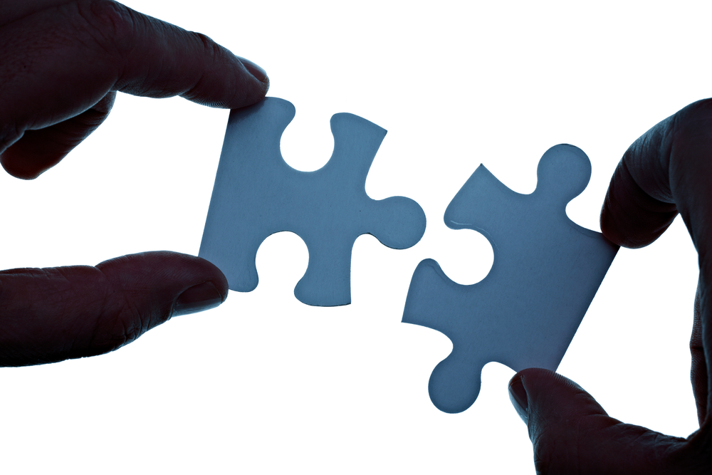 Hands assembling two jigsaw pieces together