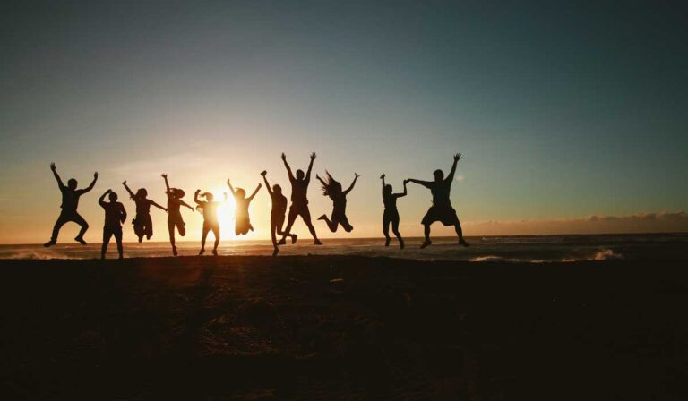 group jumping in the air on a beach at sunset