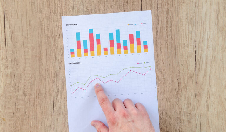 Hand on business graph, pointing to data spike